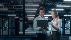 man-and-woman-reviewing-information-on-laptop-in-a-data-center man-and-woman-reviewing-information-on-laptop-in-a-data-center