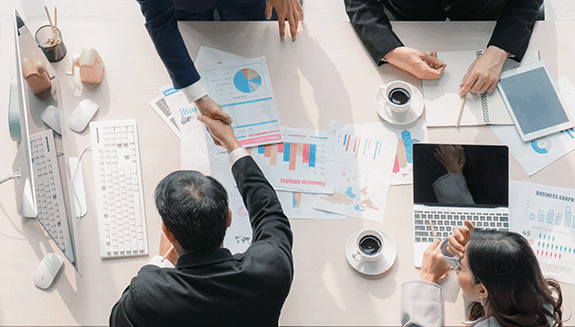 1660317240718 Fourbusinesspeoplemakingagreementovertablewithpapersfeaturingdatacharts