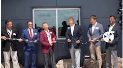 Photo-of-Chris-Lauer-Brian-Holmer-Rob-Stordahl-Dave-Doherty-Steve-Grove-and-Ramesh-Babu-cutting-digi-reel-in-front-of-new-distribution-center-building