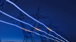 High-voltage electric transmission tower with glowing current line