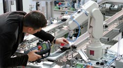 Man is holding teach panel to control a robotic arm, which is integrated on smart factory production line Man is holding teach panel to control a robotic arm, which is integrated on smart factory production line