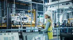 Car Factory: Female Automotive Engineer Wearing Hard Hat, Standing, Using Laptop Car Factory: Female Automotive Engineer Wearing Hard Hat, Standing, Using Laptop