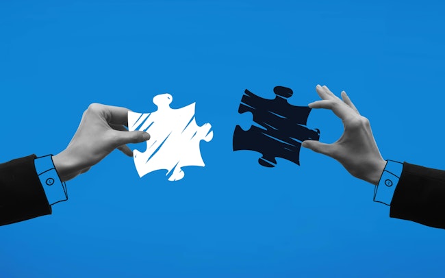 Hands holding puzzle pieces and trying to connect it against blue background.