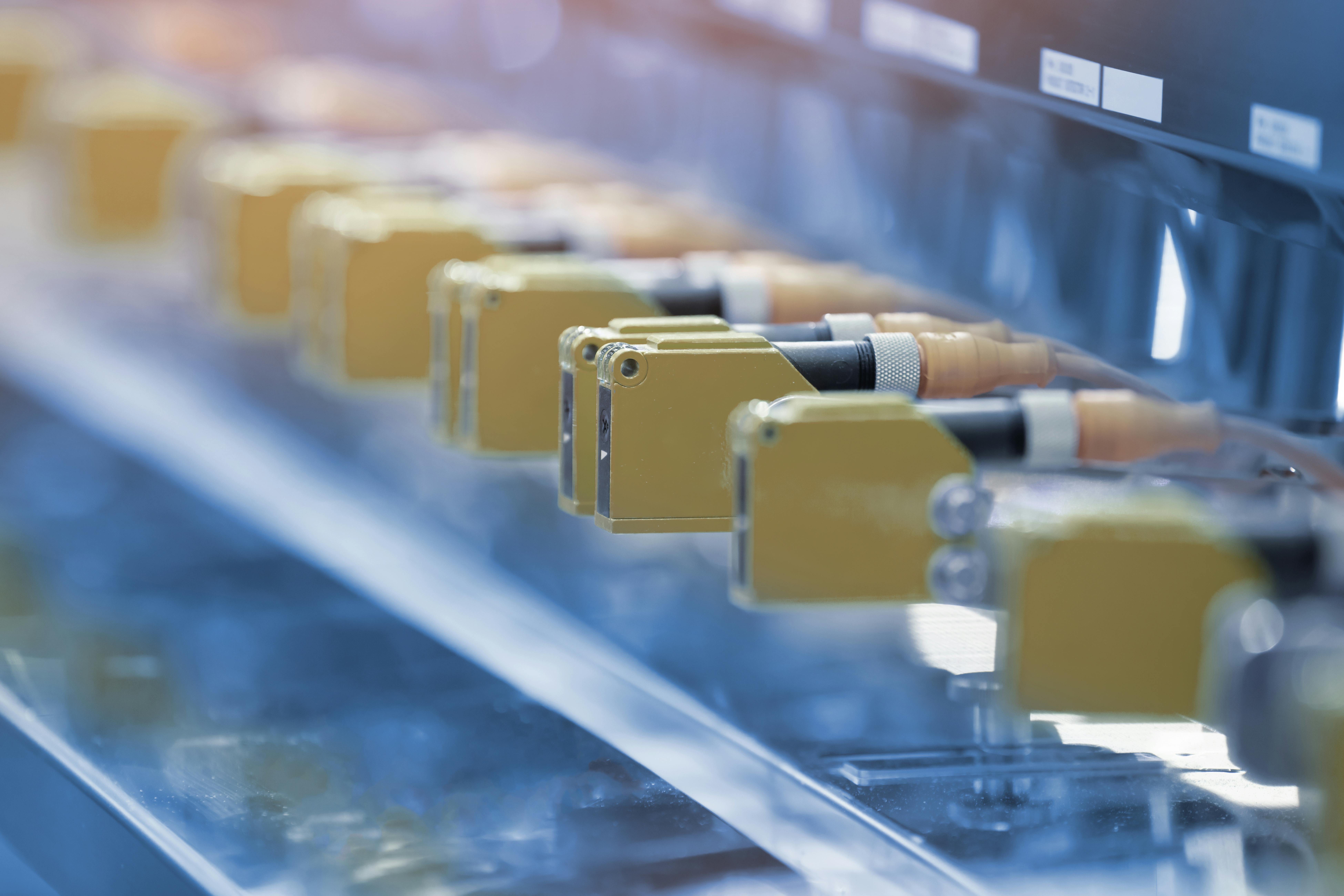 Photoelectric Sensor installed in a row of industrial machine in a factory. Photo sensor for object detection in machine factory.