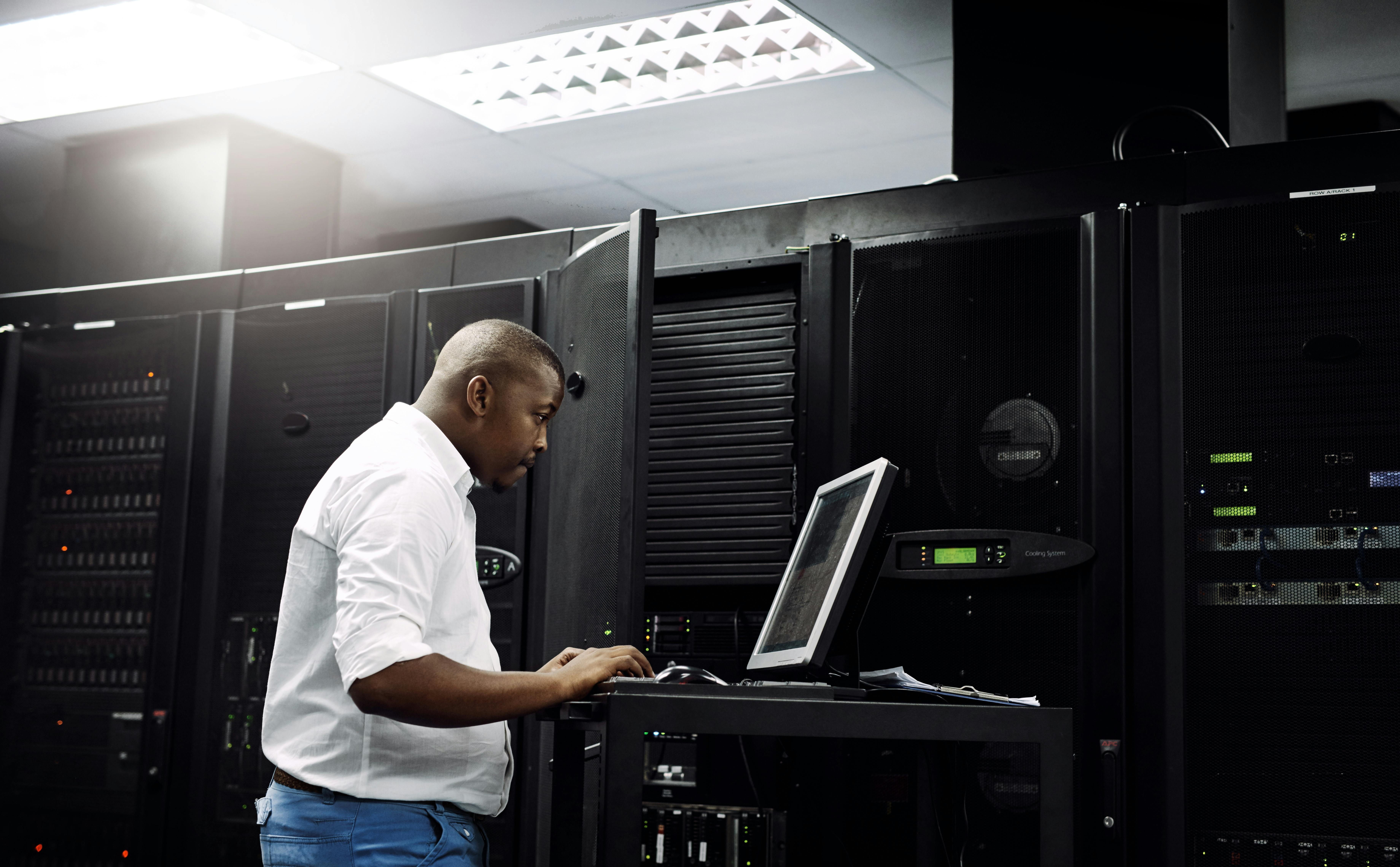 Server room, black man or coding on computer for programming or digital error in data center. Cybersecurity, support or technician typing online for fixing, troubleshooting or software development