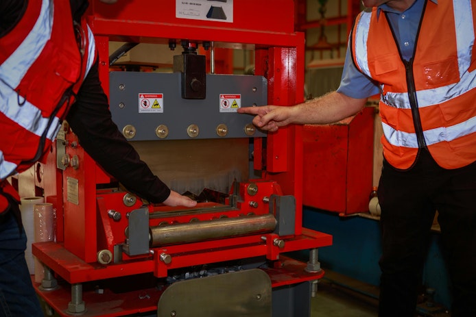 The manager is explaining the precautions and safety warning signs. attached to the machine for the engineering team in sheet steel factory Safety symbol concept in the work industry, engineering.