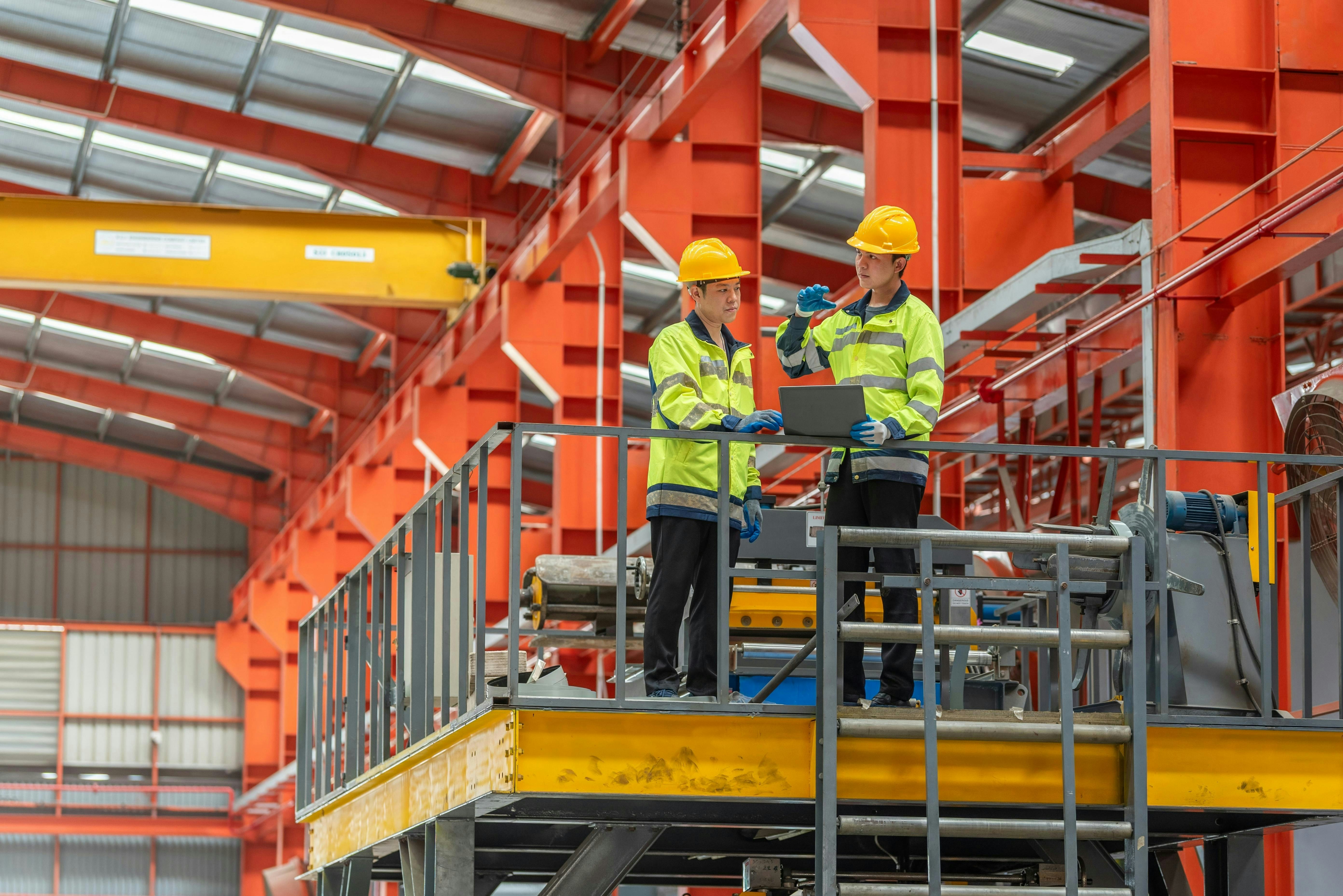 industrial apprenticeship. mentor teaching new employees trainee operating machine looking monitors and check machinery. Two industrial engineer technician In factory explain operating machine.