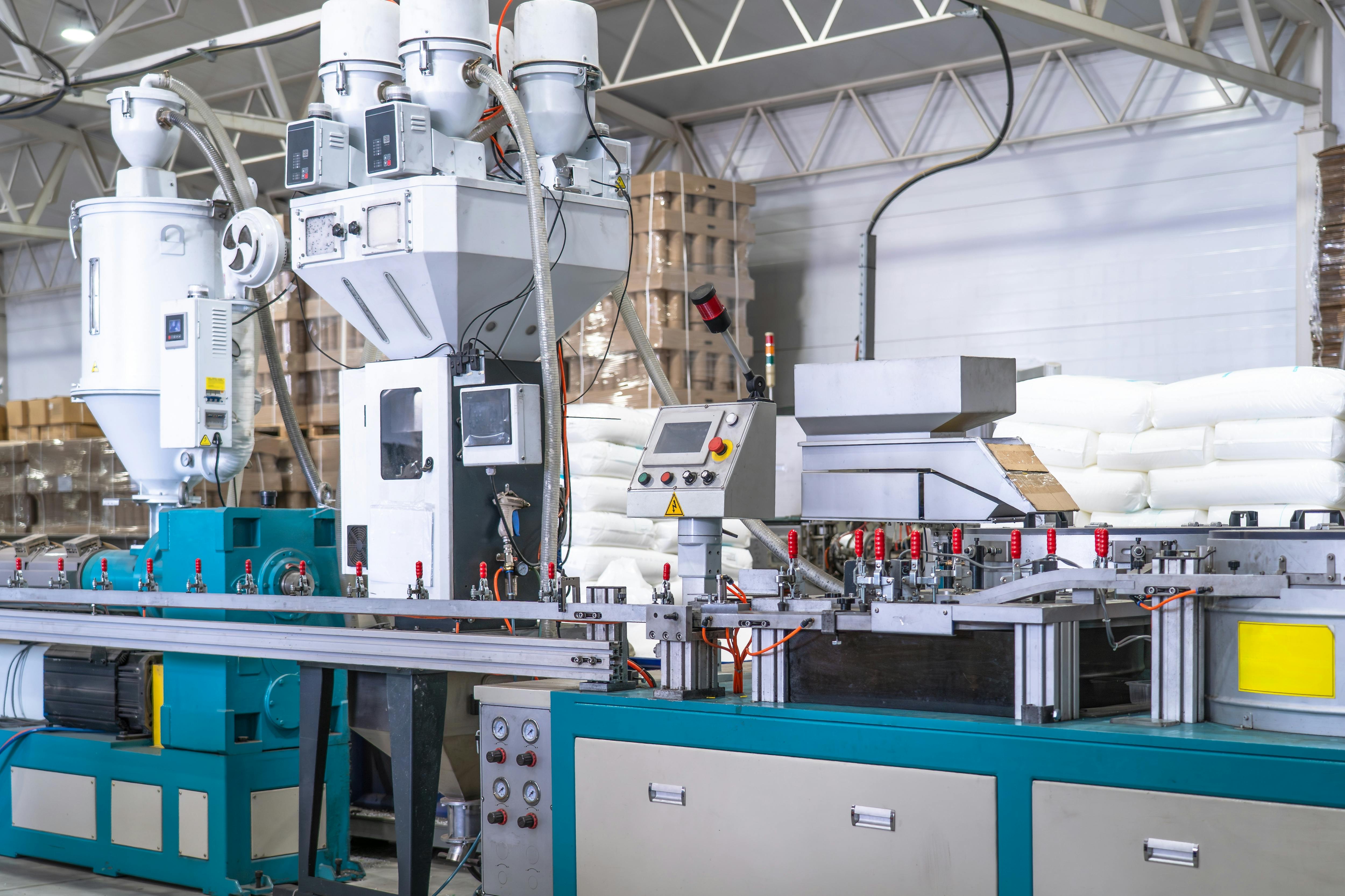 Industrial plastic extrusion machine in modern factory, automated production line with control panel, pneumatic system and material feeders, plastic processing equipment for manufacturing