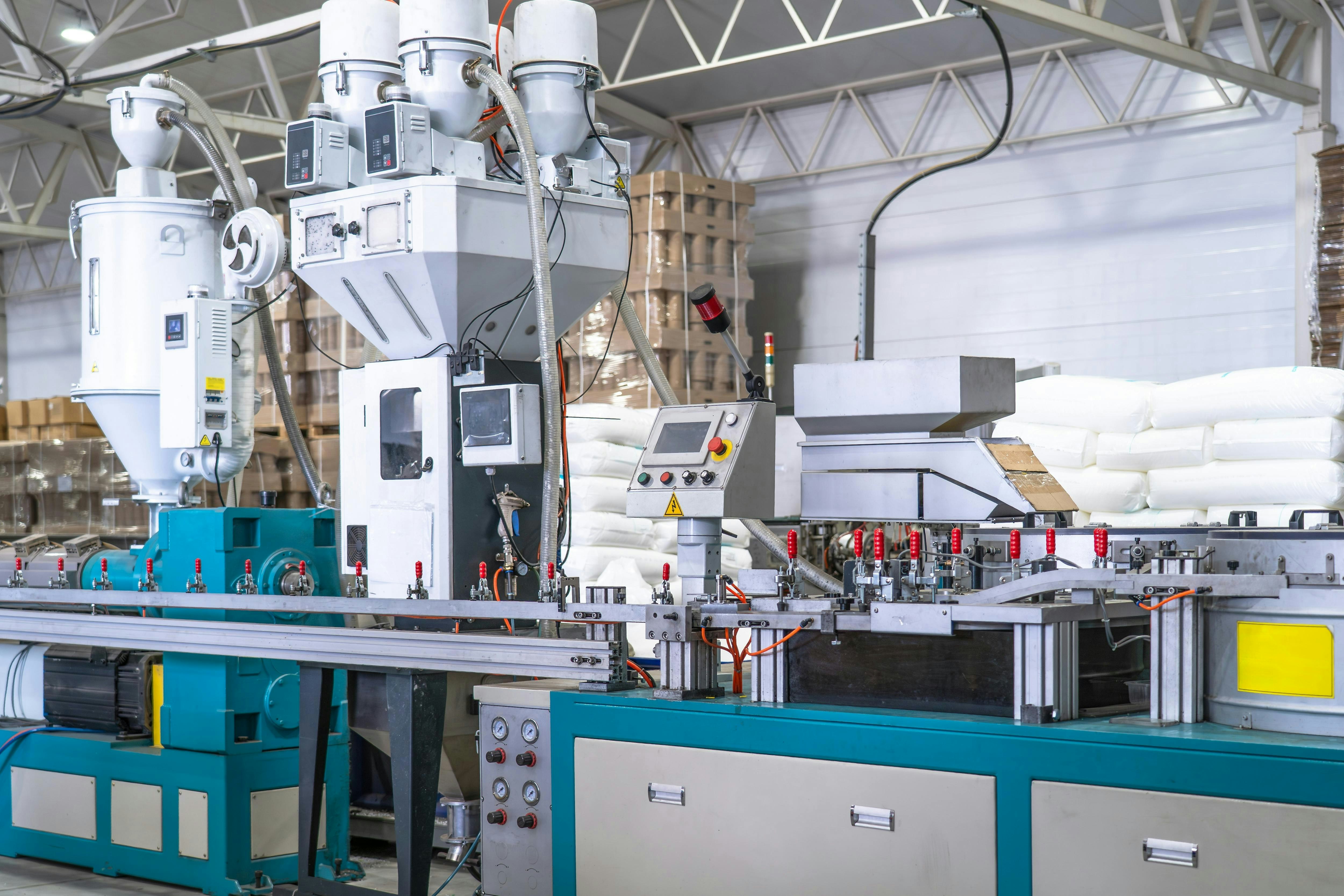 Industrial plastic extrusion machine in modern factory, automated production line with control panel, pneumatic system and material feeders, plastic processing equipment for manufacturing