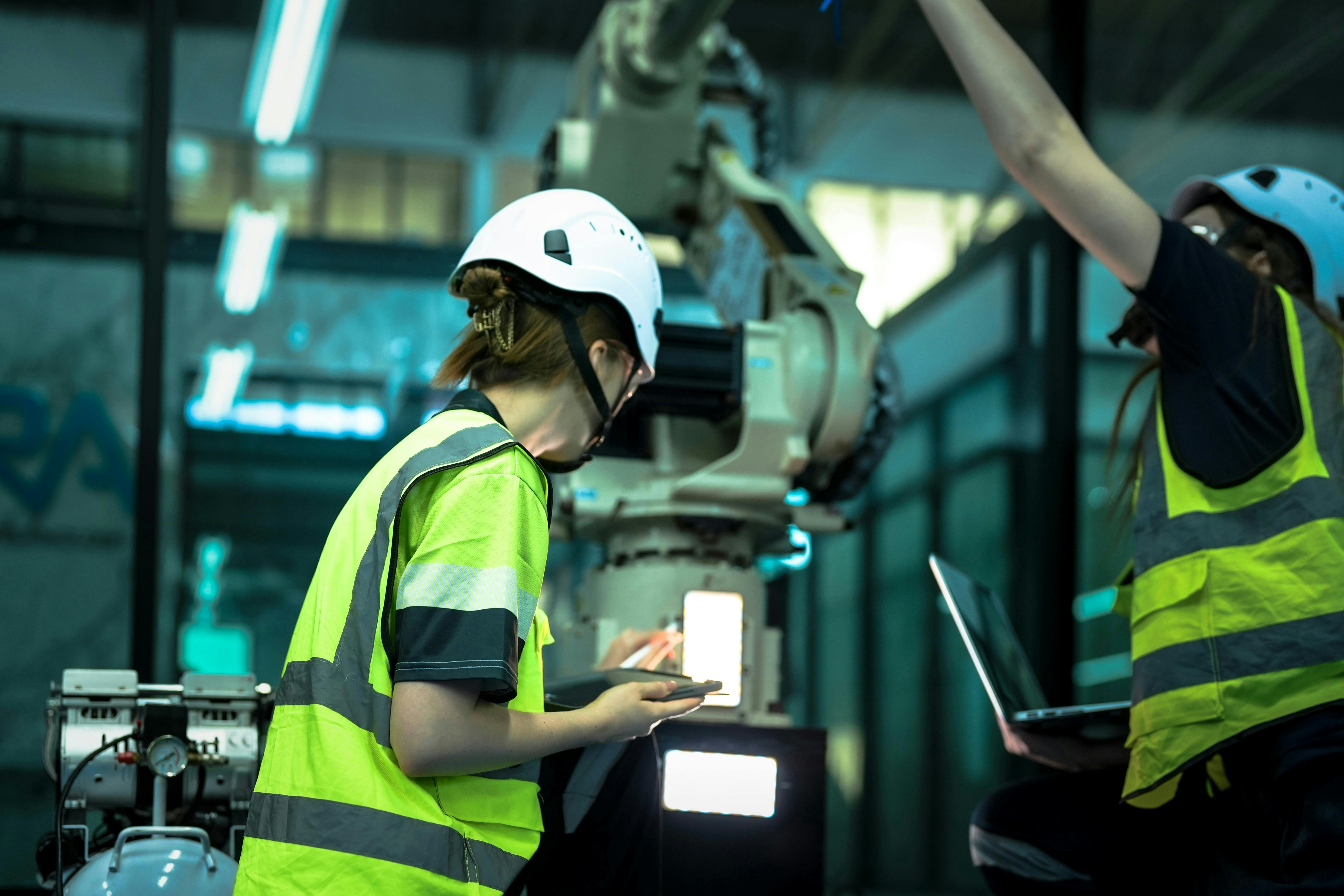 A robotics engineer uses a tablet to program a robot with a machine vision system, while her colleague calibrates the end-of-arm tooling on another unit in a system integration lab.