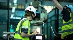 A robotics engineer uses a tablet to program a robot with a machine vision system, while her colleague calibrates the end-of-arm tooling on another unit in a system integration lab.