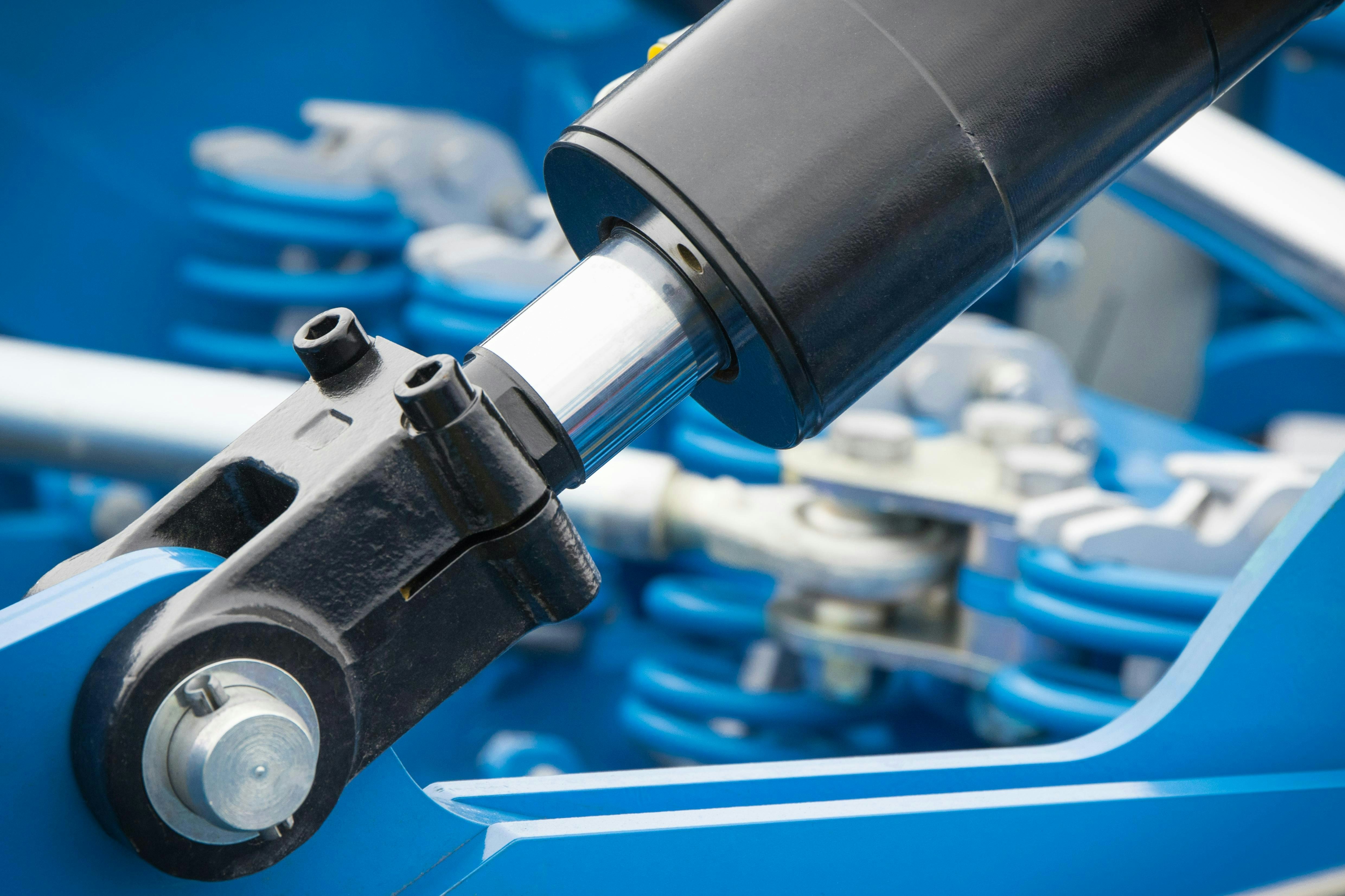 Black piston or actuator as part of blue pneumatic or hydraulic machine. Technology and engineering