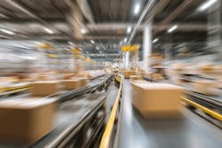 Fast-moving cardboard boxes on conveyor belts in a large warehouse or distribution center. Fast-moving cardboard boxes on conveyor belts in a large warehouse or distribution center.