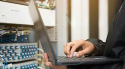 Technician using laptop in server room.
