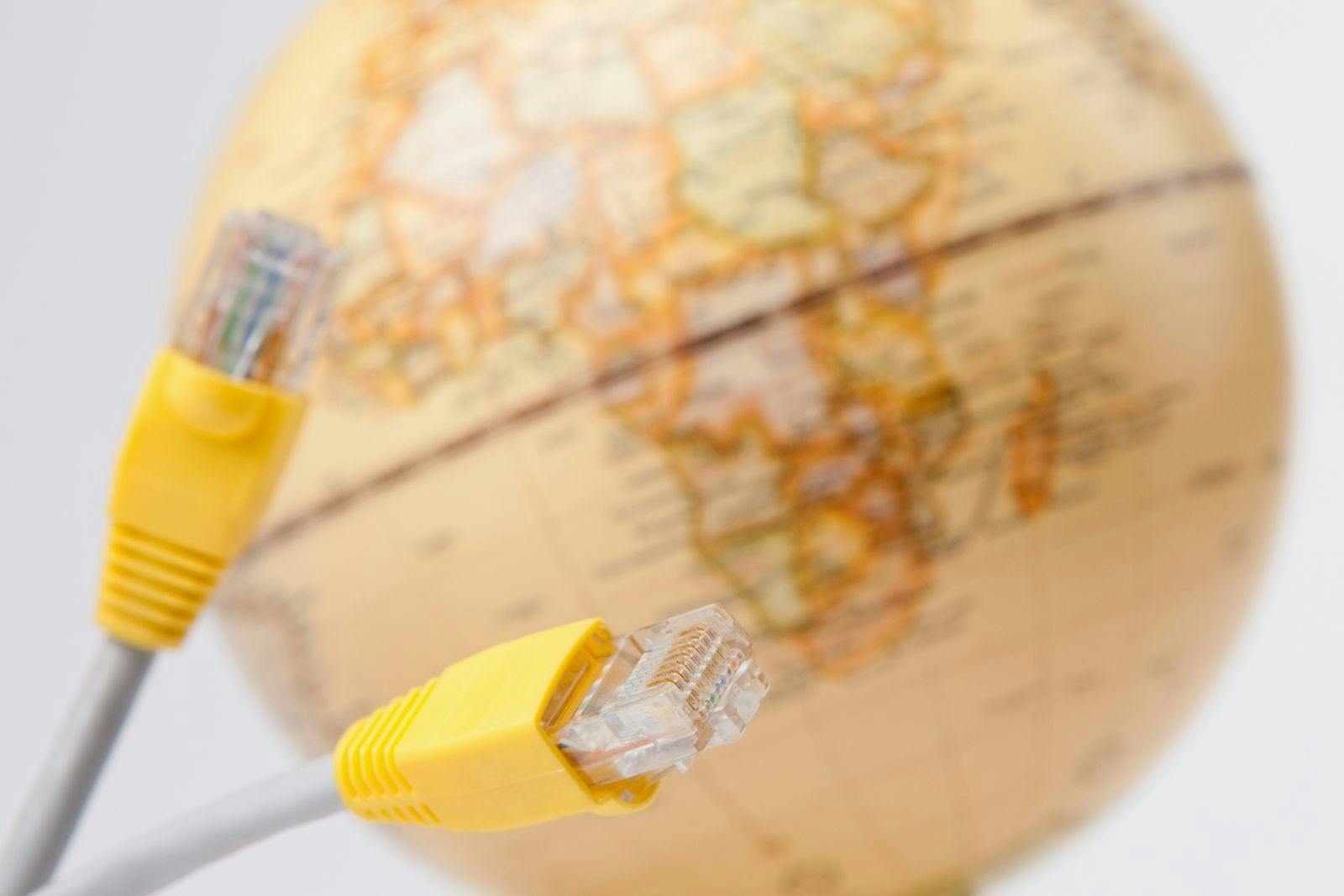 Connection between technology and geography seen through network cables and a globe