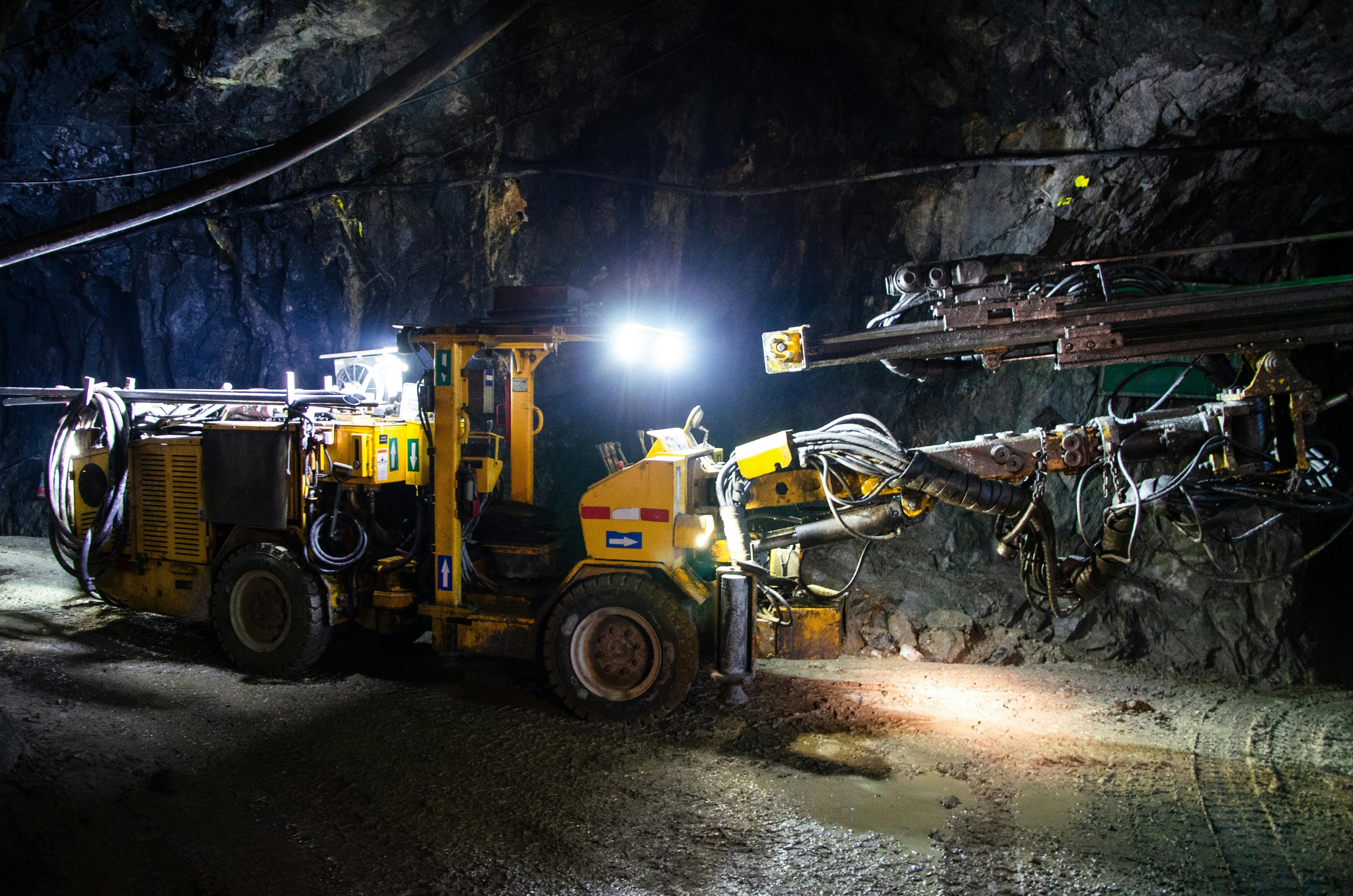Heavy drilling machinery at work in a dimly lit underground mine
