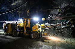 Heavy drilling machinery at work in a dimly lit underground mine Heavy drilling machinery at work in a dimly lit underground mine