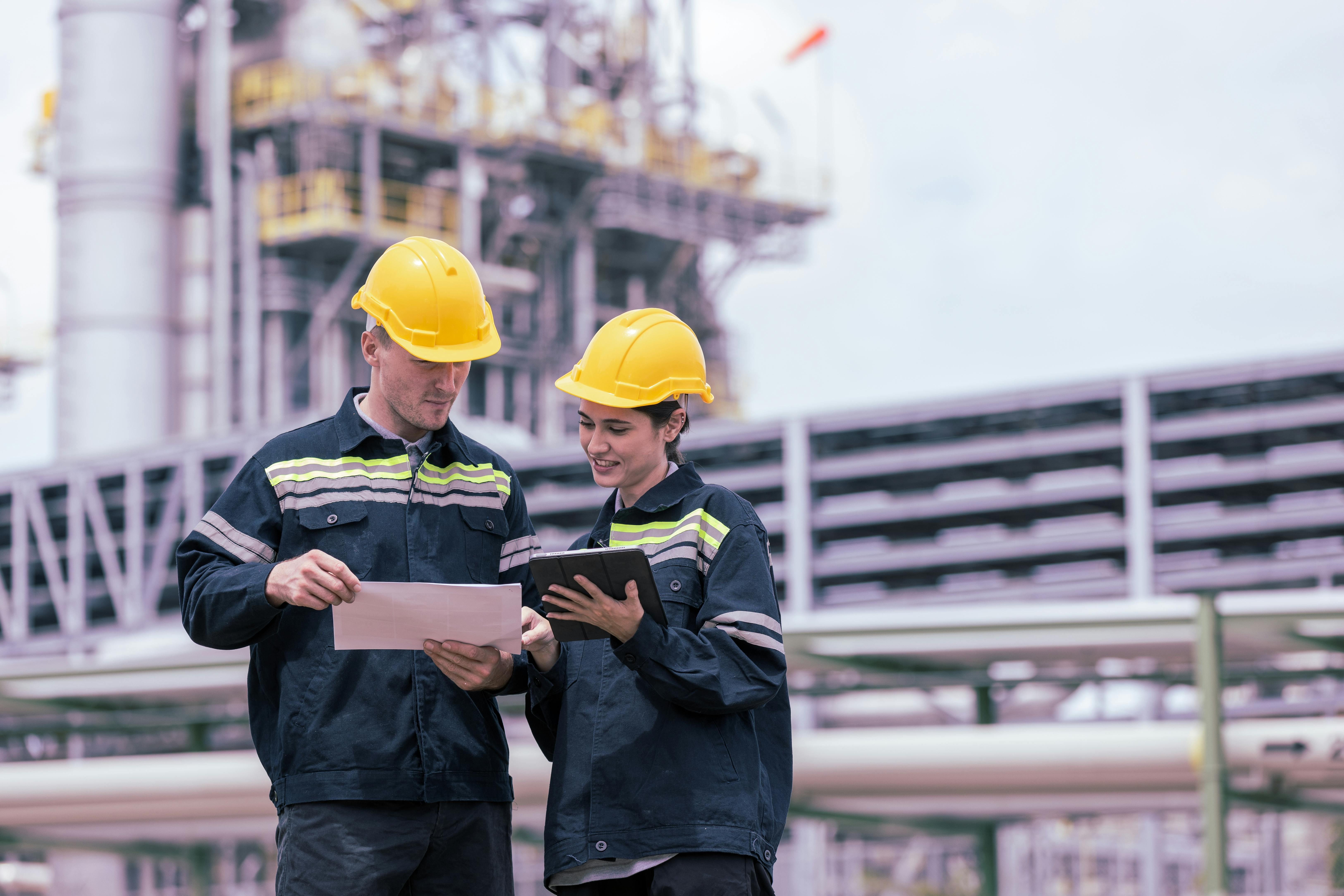 Engineers working with tablet in industry oil refinery oil, gas refinery background.