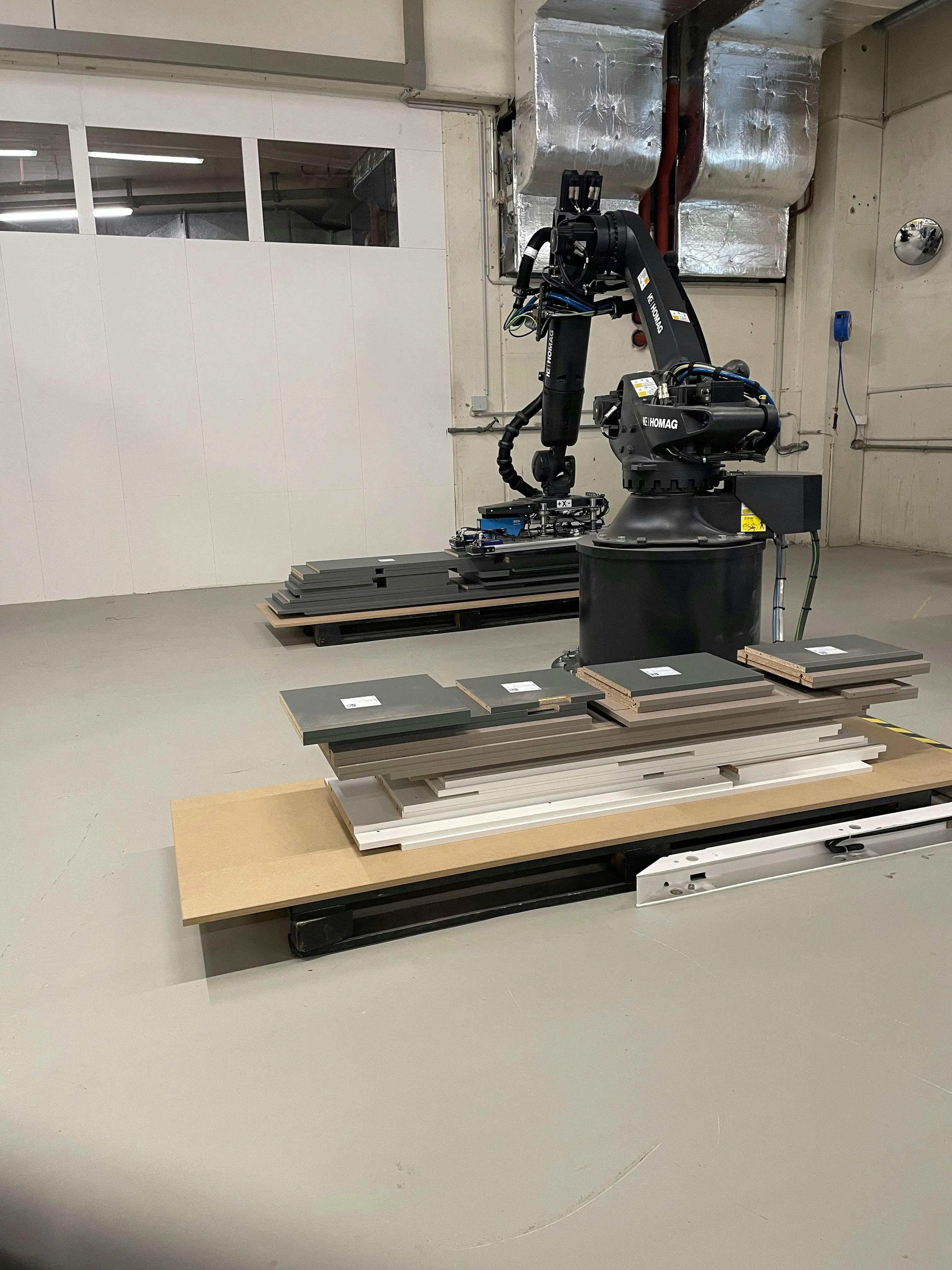 Figure 1: At the literal center of the system is a robot that picks wooden workpieces from a stack, feeds them into the CNC machine and removes and places them after processing.