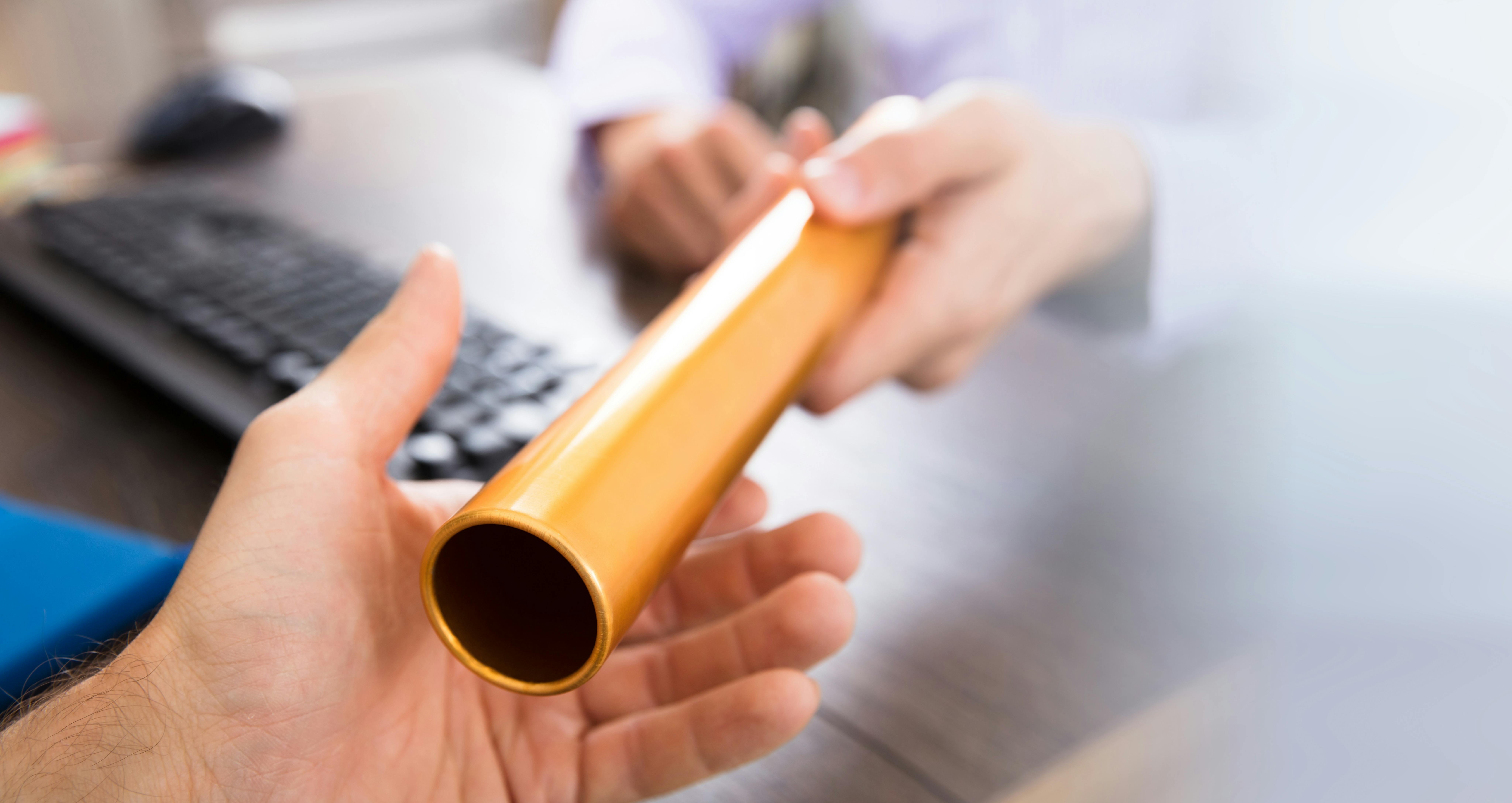 Close-up Of A Person's Hand Passing Golden Relay Baton To Businessman