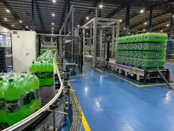 A modern beverage production line inside a large industrial factory, showcasing rows of green carbonated soft drink bottles moving along an automated conveyor system. The image highlights advanced manufacturing technology, with neatly stacked pallets of bottled drinks ready for distribution in the background. Bright overhead lighting illuminates the clean, organized facility, emphasizing efficiency, hygiene, and high-volume production. A modern beverage production line inside a large industrial factory, showcasing rows of green carbonated soft drink bottles moving along an automated conveyor system. The image highlights advanced manufacturing technology, with neatly stacked pallets of bottled drinks ready for distribution in the background. Bright overhead lighting illuminates the clean, organized facility, emphasizing efficiency, hygiene, and high-volume production.