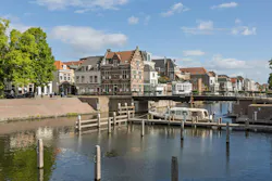 A picturesque scene in Gorinchem, Netherlands, showcasing traditional Dutch canal houses, the Peterbrug (Peter Bridge), and a house boat on the tranquil canal under a bright sky. A picturesque scene in Gorinchem, Netherlands, showcasing traditional Dutch canal houses, the Peterbrug (Peter Bridge), and a house boat on the tranquil canal under a bright sky.