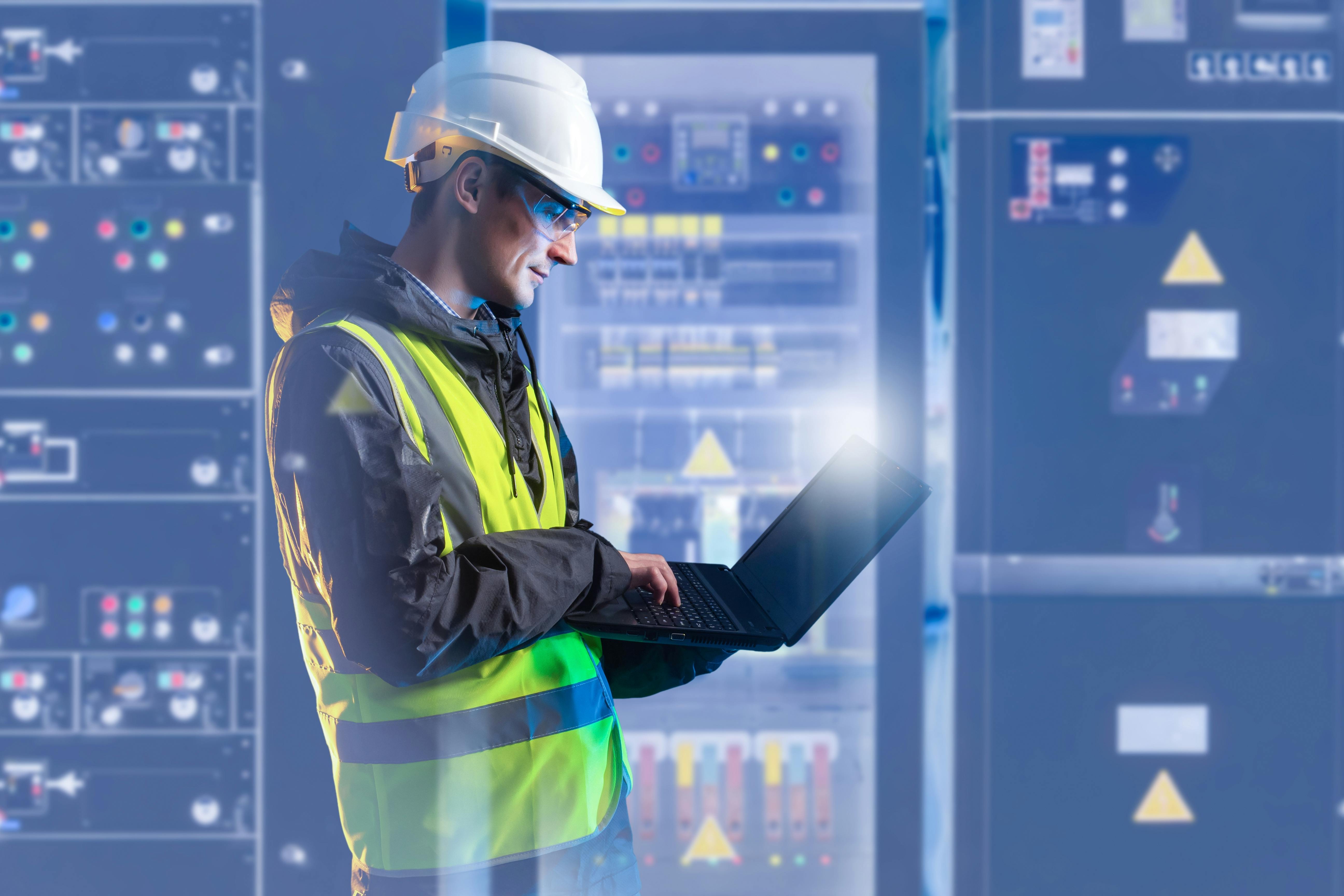 Electrical engineering, technician monitors control panels and analyzes system data on laptop. Industrial power equipment operation, safety inspection and maintenance in energy facility.
