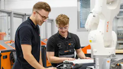 Two KUKA engineers examine robot programming in a robotics factory.