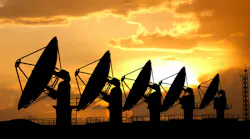 Silhouettes of radars antennas on the ground against sunset sky. Row of large satellite stations dish telescopes.