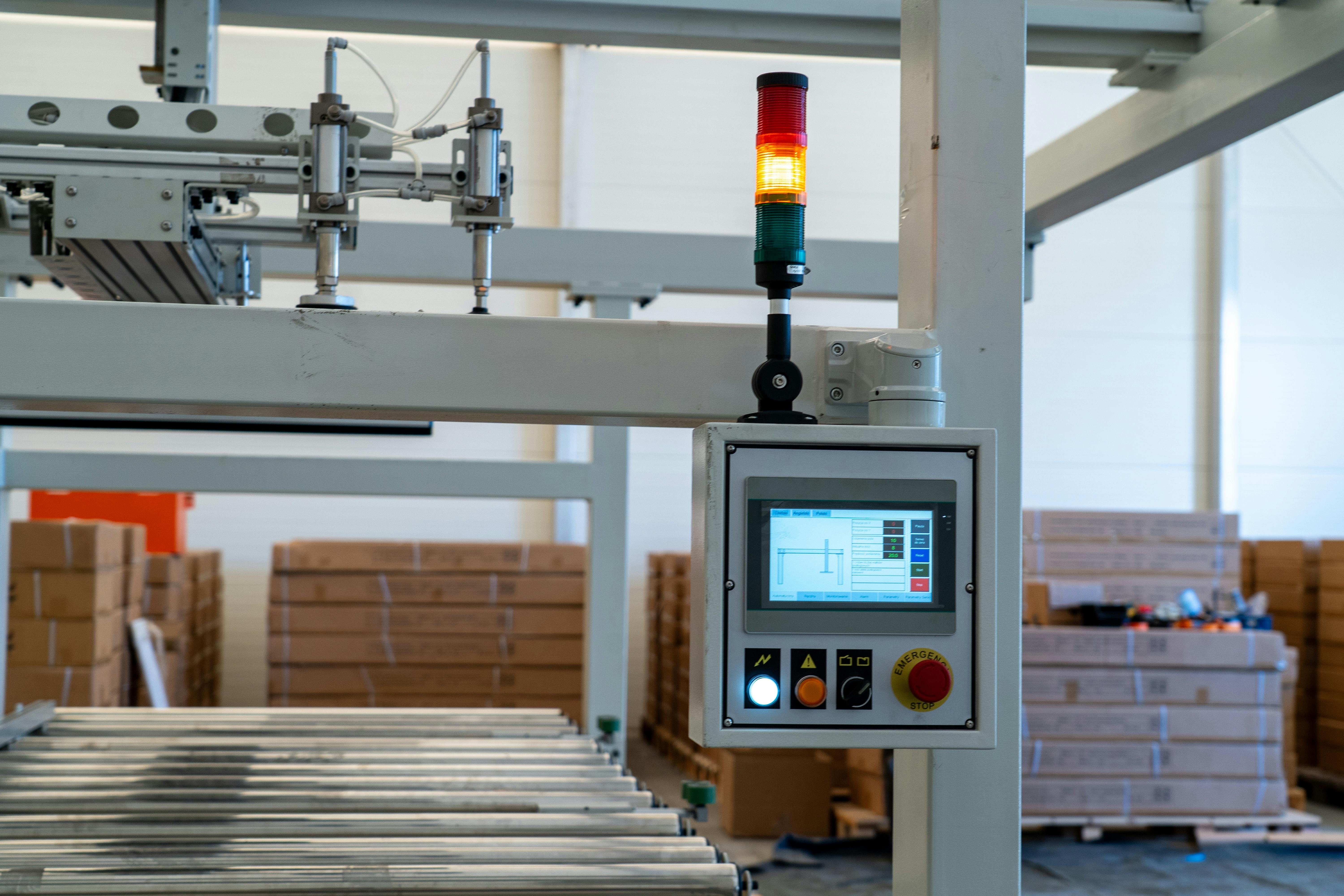 Industrial control panel with HMI display and signal tower on conveyor line
