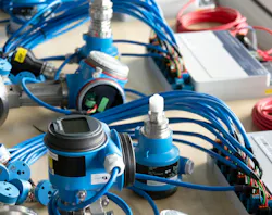 Blue Ethernet-APL devices laid out across a table with wires plugged into devices.