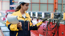 Female engineer carefully inspects roofing sheet production machine while holding blueprint at steel factory. Represents responsibility, accuracy, and industrial professionalism.