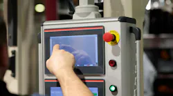 Operator working with touchscreen control panel of industrial machine.