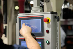Operator working with touchscreen control panel of industrial machine.