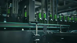 Rows of green glass bottles gliding along a conveyor belt inside an industrial brewery, moving through quality control machinery designed for efficient production and inspection