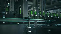 Rows of green glass bottles gliding along a conveyor belt inside an industrial brewery, moving through quality control machinery designed for efficient production and inspection